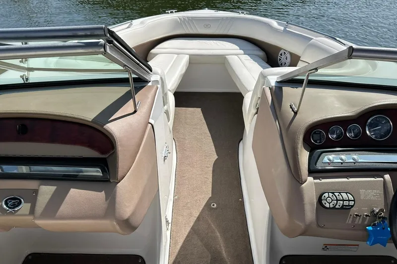 Slide: The Image of 2007 Cobalt 232 boat interior with beige seating and dashboard, on calm water. - 35