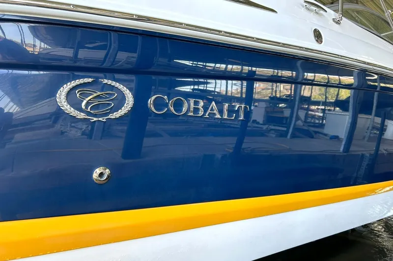 Slide: The Image of 2007 Cobalt 232 boat with blue and yellow exterior, docked indoors. - 48