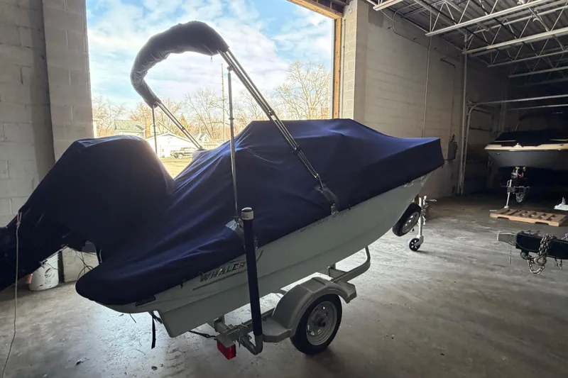 Slide: The Image of 2023 Boston Whaler 130 Super Sport boat covered in a garage setting. - 6