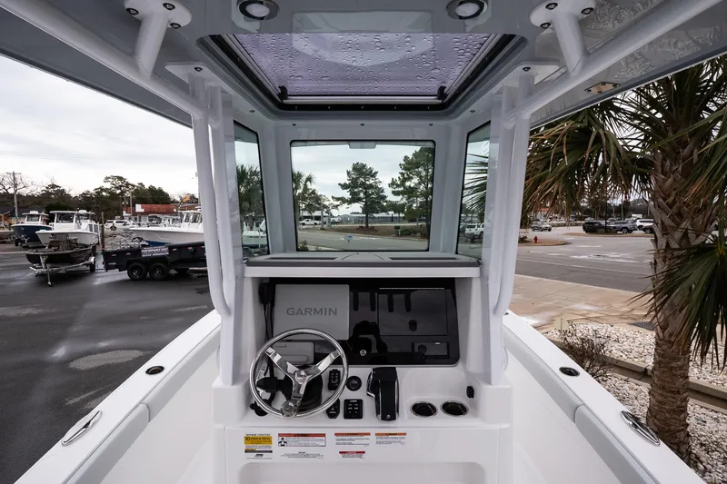 Slide: The Image of 2026 Blackfin 242 HB boat helm with Garmin system, parked near palm trees. - 12