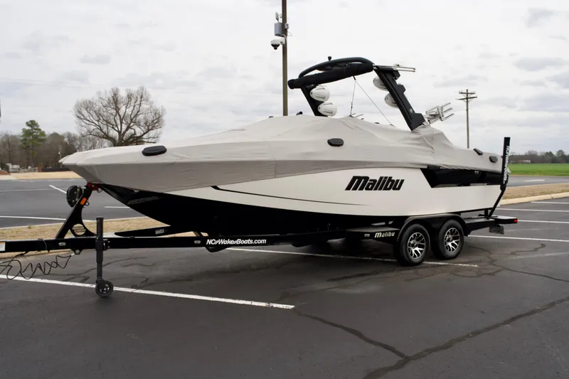 Slide: The Image of 2020 Malibu Wakesetter 24 MXZ boat covered on trailer in parking lot. - 22