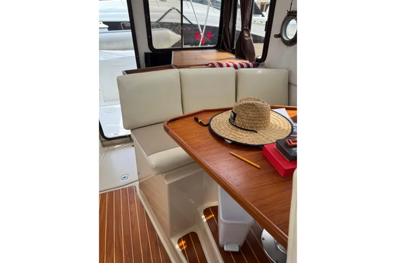 Slide: The Image of Interior of 2009 Ranger Tugs R-29 with wooden table, straw hat, and cushioned seating. - 14