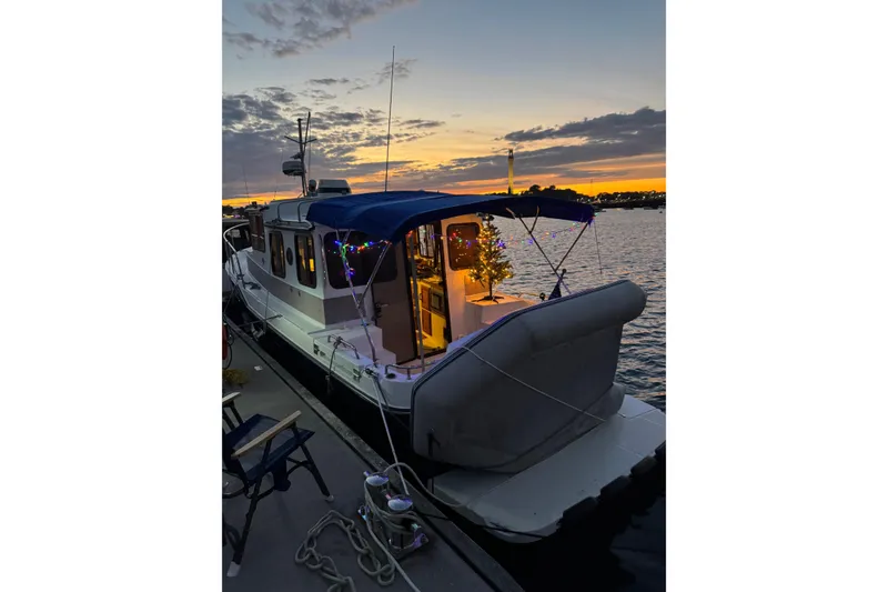 Slide: The Image of 2009 Ranger Tugs R-29 boat docked at sunset, decorated with festive lights. - 2