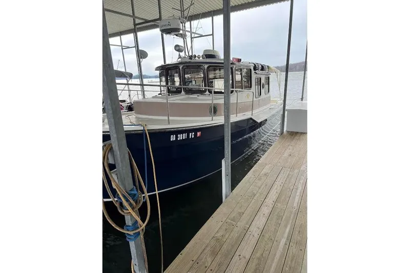 Slide: The Image of 2009 Ranger Tugs R-29 docked under a covered marina on a calm lake. - 9