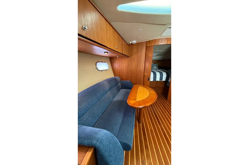 Slide: The Image of 2007 Tiara Yachts 3900 Sovran interior with blue sofa, wooden table, and striped bedding. - 48