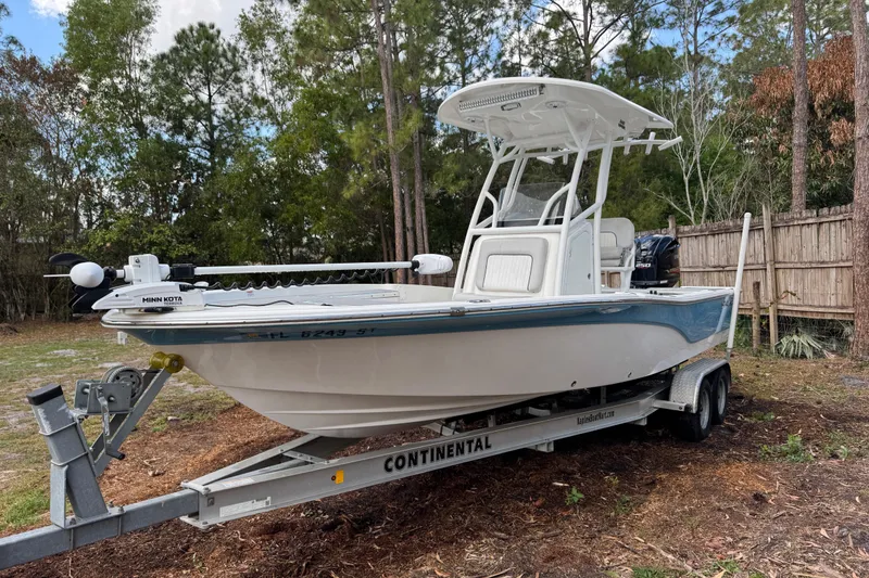 Slide: The Image of 2019 Sea Fox 240 Viper boat on trailer, parked outdoors near trees and fence. - 2