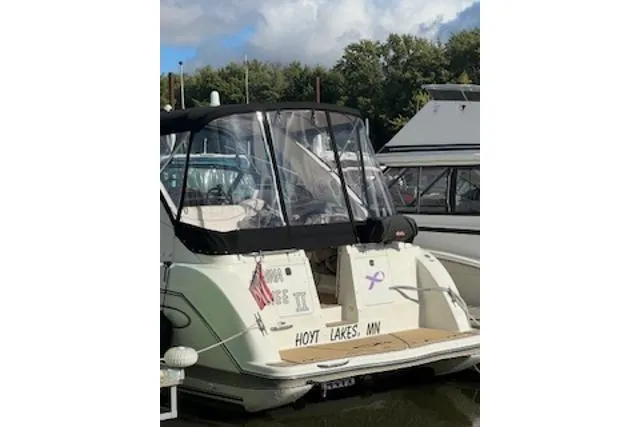 Slide: The Image of 2000 Maxum 3300 SCR boat docked, featuring a covered cockpit and American flag. - 33