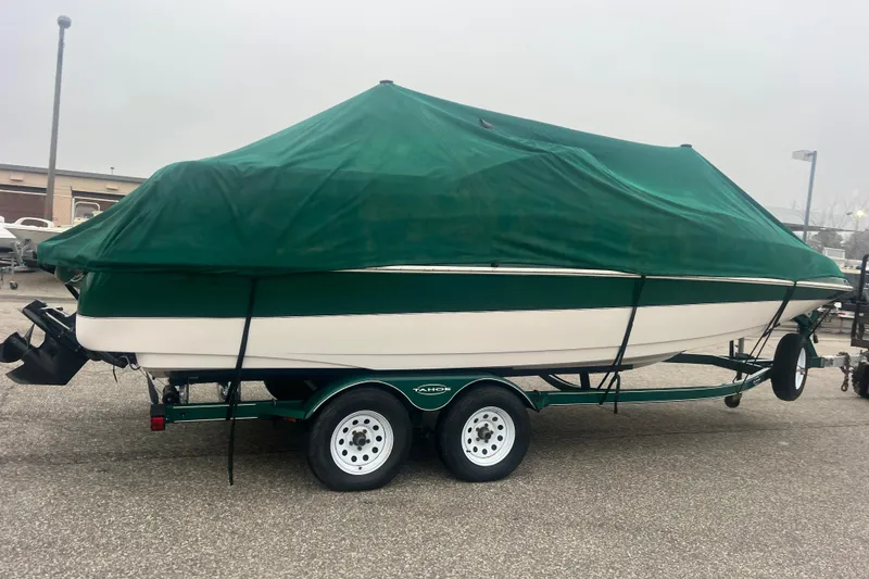 Slide: The Image of 2005 Tahoe 234 boat covered with green tarp on trailer in parking lot. - 41