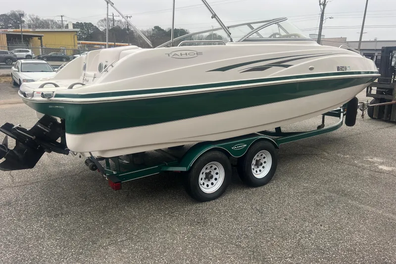 Slide: The Image of 2005 Tahoe 234 boat on trailer, green and white design, parked outdoors. - 7