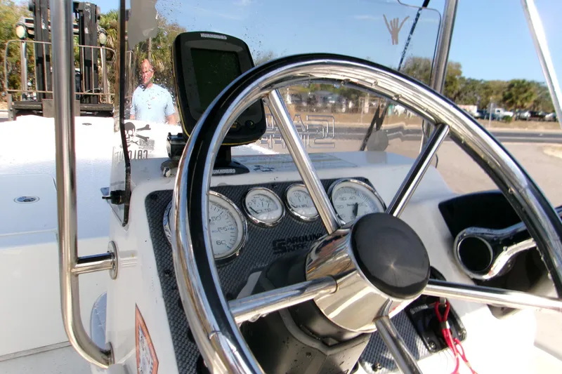 Slide: The Image of 2012 Carolina Skiff JVX16CC boat dashboard with steering wheel and gauges. - 2