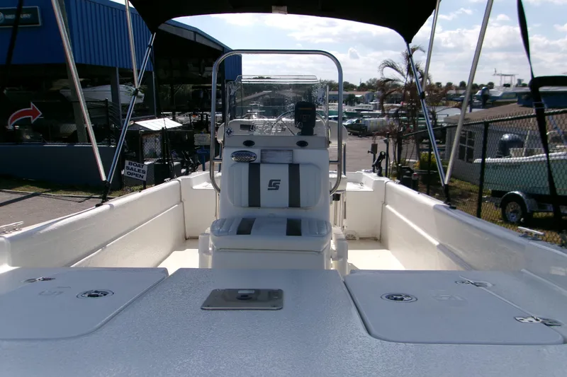 Slide: The Image of 2012 Carolina Skiff JVX16CC boat interior with console and seating, docked at a marina. - 5
