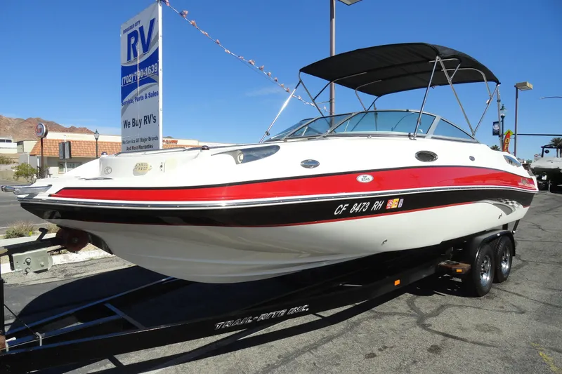Slide: The Image of 2005 Kayot S245 boat on trailer at RV dealership under clear blue sky. - 2