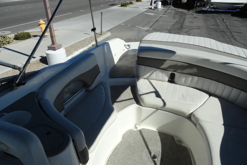 Slide: The Image of 2005 Kayot S245 boat interior with white seating and gray accents, parked near a street. - 23