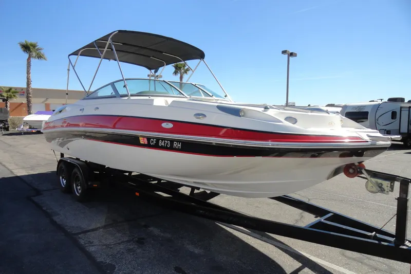 Slide: The Image of 2005 Kayot S245 boat on trailer, parked outdoors under clear blue sky. - 4