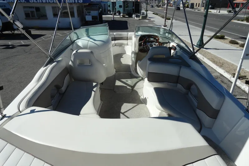 Slide: The Image of 2005 Kayot S245 boat interior with spacious seating and steering wheel, parked outdoors. - 6