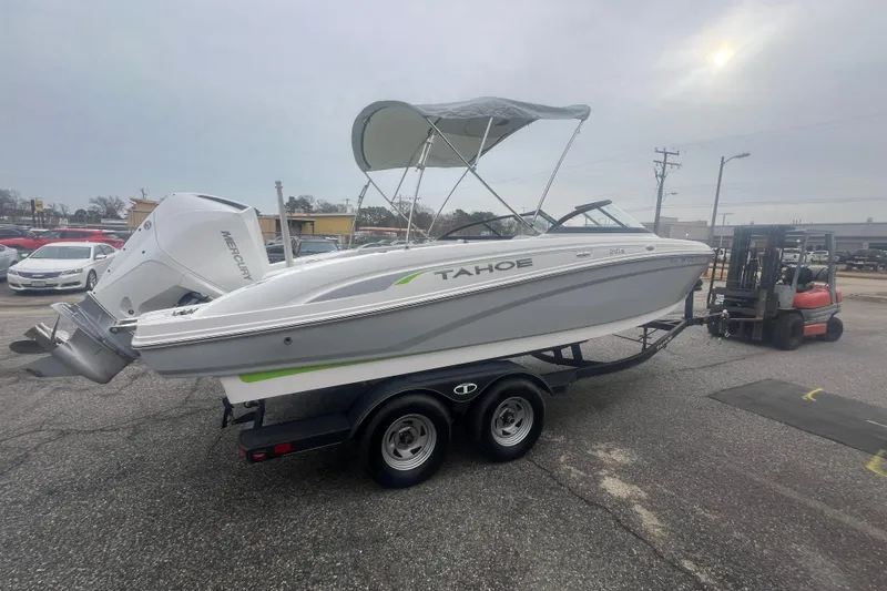 Slide: The Image of 2024 Tahoe 210 S boat on trailer with Mercury engine, parked outdoors. - 11