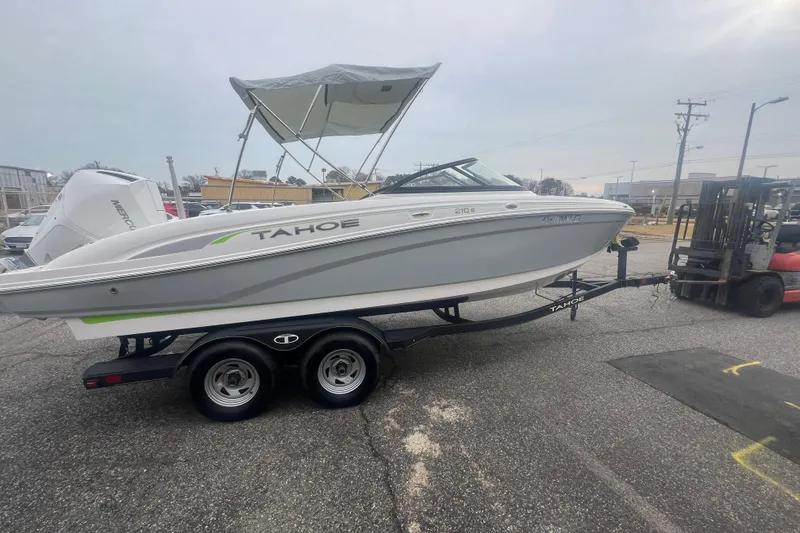Slide: The Image of 2024 Tahoe 210 S boat on trailer, parked outdoors with a forklift nearby. - 12