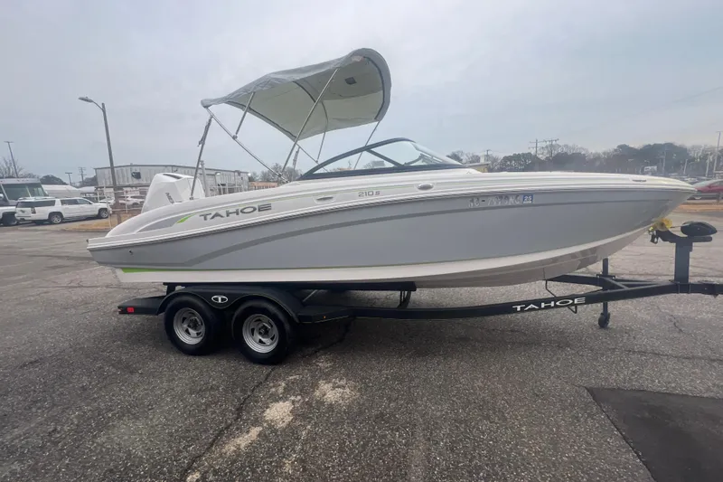 Slide: The Image of 2024 Tahoe 210 S boat on trailer, parked outdoors with canopy. - 13