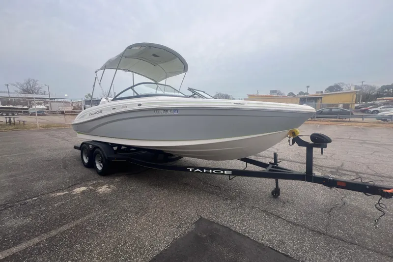 Slide: The Image of 2024 Tahoe 210 S boat on trailer, parked outdoors under cloudy sky. - 14