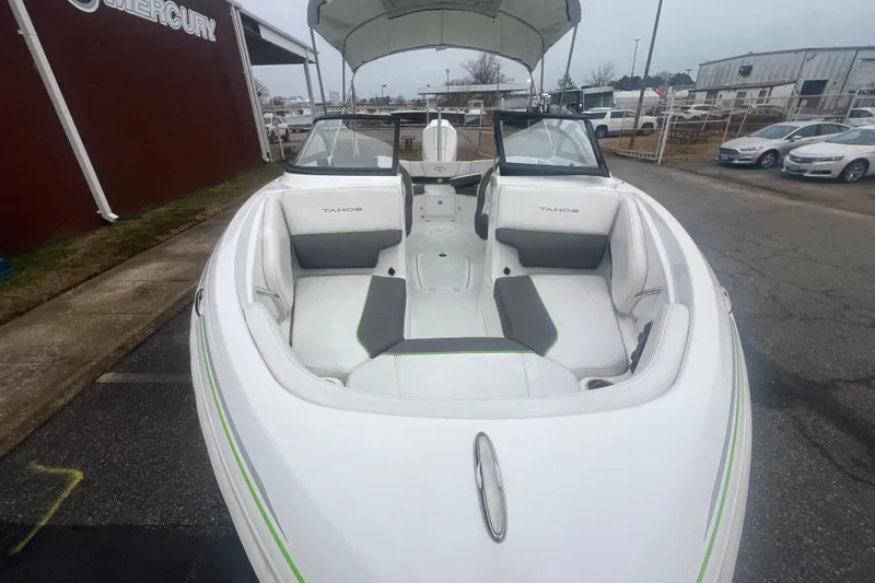 Slide: The Image of 2024 Tahoe 210 S boat with open bow seating and canopy, parked outdoors. - 16