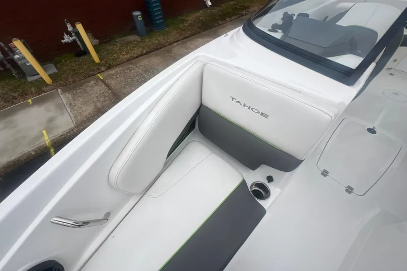 Slide: The Image of 2024 Tahoe 210 S boat interior with white and gray seating, cup holder, and windshield. - 21
