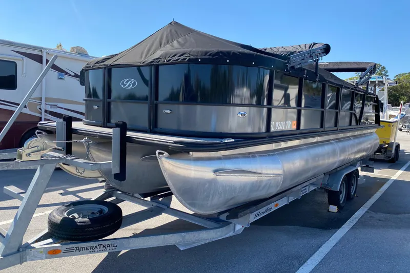 Slide: The Image of 2024 Bentley Pontoons Legacy Swingback on trailer, covered and parked outdoors. - 22