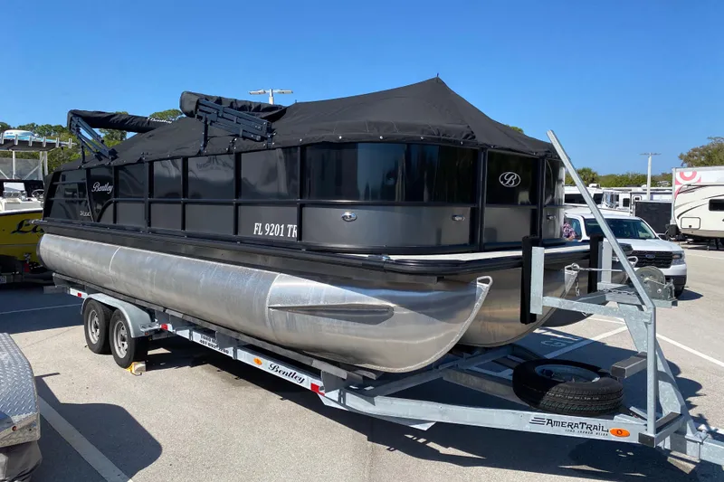 Slide: The Image of 2024 Bentley Pontoons Legacy Swingback on trailer, covered, in parking lot. - 23