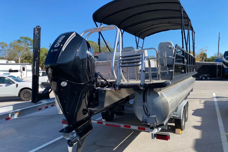 Slide: The Image of 2024 Bentley Pontoons Legacy Swingback with powerful outboard motor, parked on a trailer. - 3