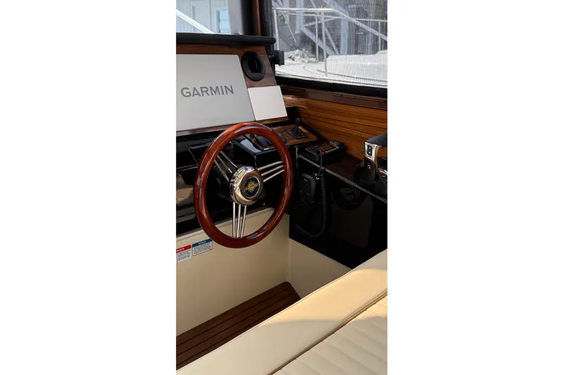 Slide: The Image of 2026 Ranger Tugs R-27 helm with Garmin navigation, wooden steering wheel, and modern controls. - 13
