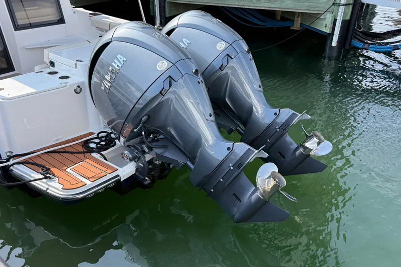 Slide: The Image of Twin Yamaha outboard engines on a 2026 Ranger Tugs R-27 boat, docked in water. - 2