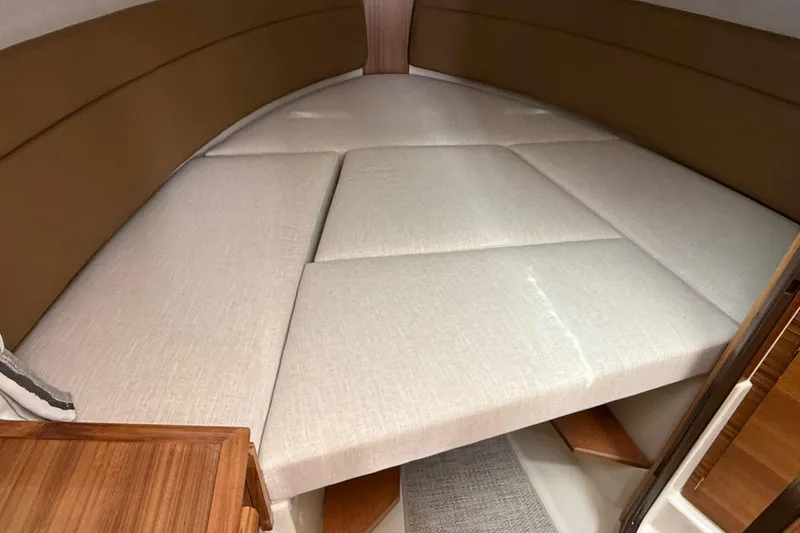 Slide: The Image of 2026 Ranger Tugs R-27 interior cabin with beige cushioned seating and wooden accents. - 32