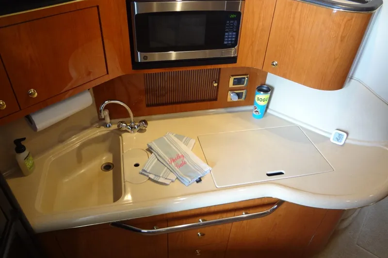 Slide: The Image of 2001 Sea Ray 380 Sundancer kitchen with sink, microwave, and wooden cabinetry. - 30