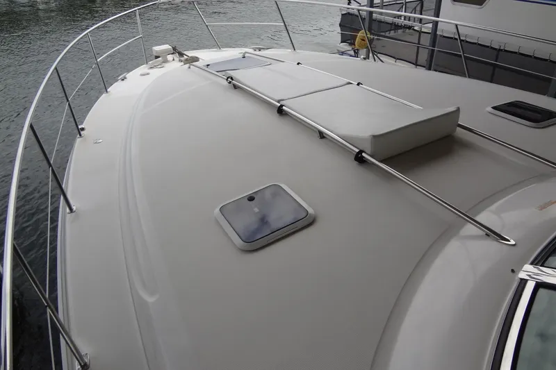 Slide: The Image of 2001 Sea Ray 380 Sundancer boat deck with railing and hatch, docked by water. - 9