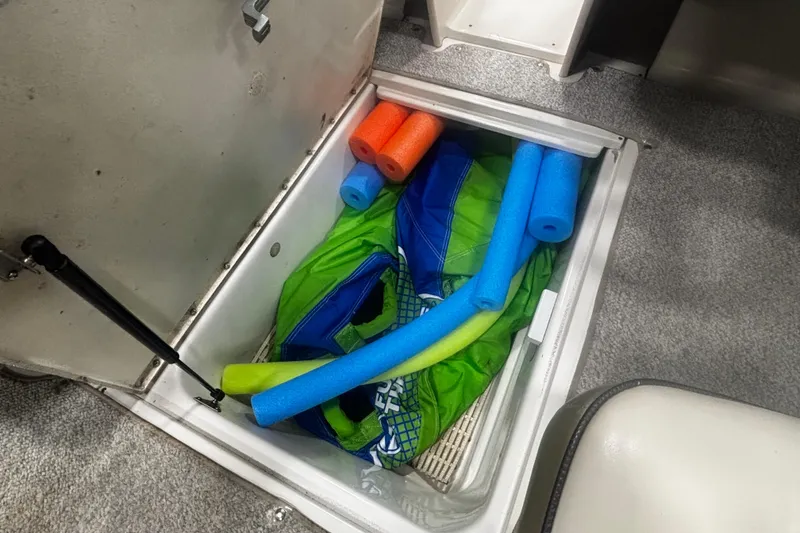 Slide: The Image of Storage compartment in 2004 Sea Ray 185 Bow Rider with pool noodles and life jacket. - 32