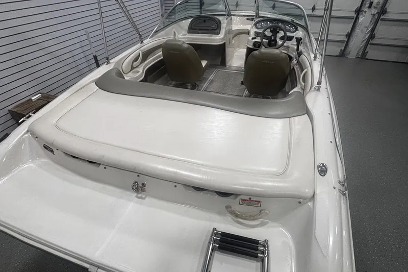 Slide: The Image of 2004 Sea Ray 185 Bow Rider boat interior with seating and steering wheel in a garage. - 34