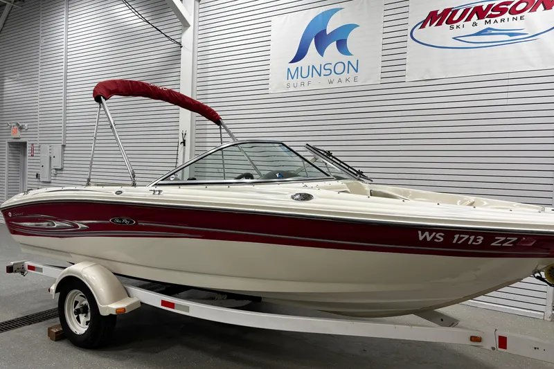 Slide: The Image of 2004 Sea Ray 185 Bow Rider boat with red accents on a trailer indoors. - 4