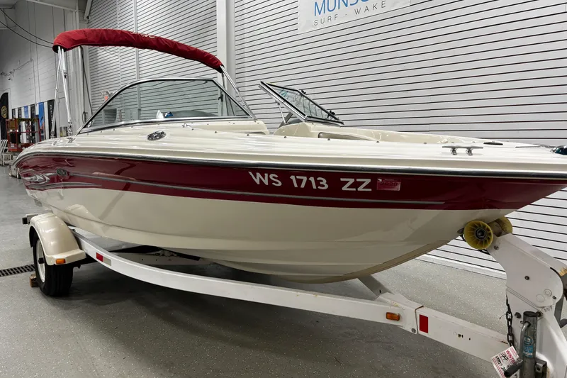 Slide: The Image of 2004 Sea Ray 185 Bow Rider boat with red accents on a trailer in a showroom. - 5