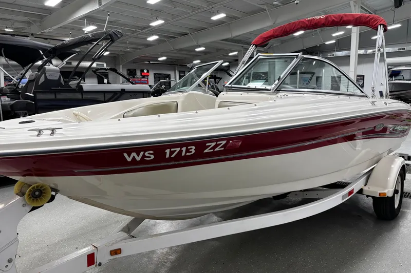 Slide: The Image of 2004 Sea Ray 185 Bow Rider boat with red accents on a trailer in a showroom. - 6