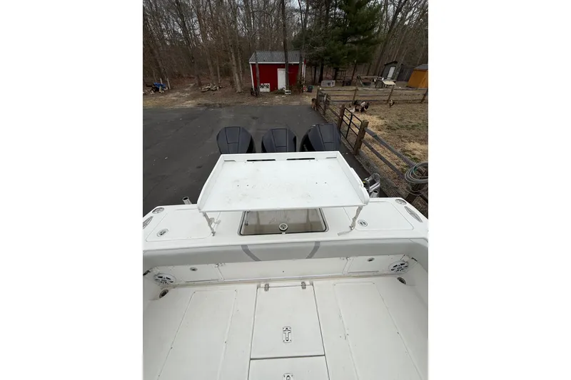 Slide: The Image of 2006 SeaVee 340B boat with triple engines, parked near a red shed and wooded area. - 32