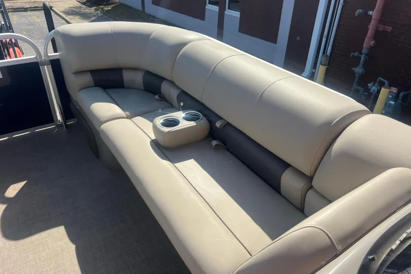 Slide: The Image of 2023 Sun Tracker Party Barge 20 DLX interior with beige seating and cup holders. - 19