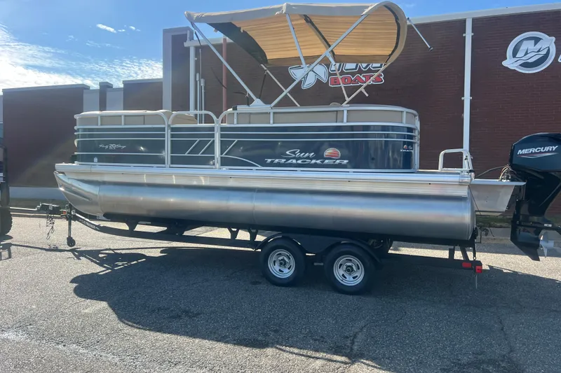 Slide: The Image of 2023 Sun Tracker Party Barge 20 DLX pontoon boat on trailer, parked outdoors. - 2