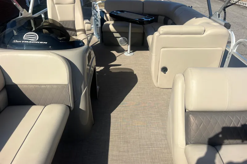 Slide: The Image of 2023 Sun Tracker Party Barge 20 DLX interior with beige seating and steering console. - 23
