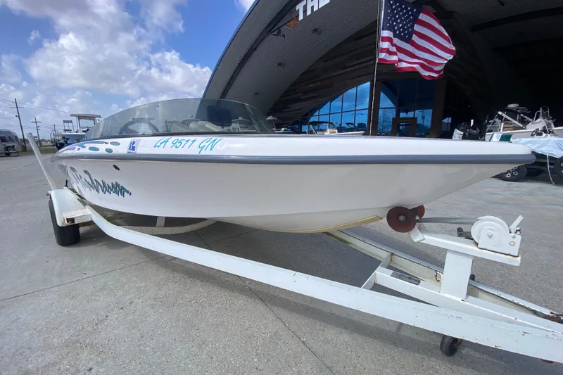 Slide: The Image of 1997 Malibu Tantrum boat on trailer, parked near a building with an American flag. - 10
