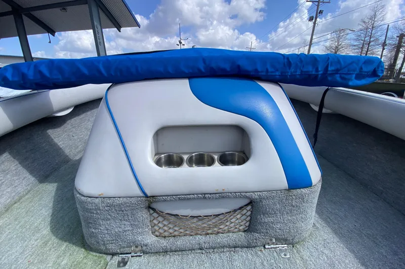 Slide: The Image of 1997 Malibu Tantrum boat interior with blue and white seating, cup holders, and storage net. - 12