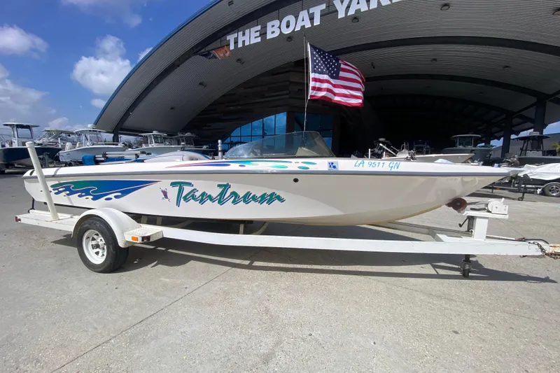 Slide: The Image of 1997 Malibu Tantrum boat on trailer with American flag, parked at The Boat Yard. - 2