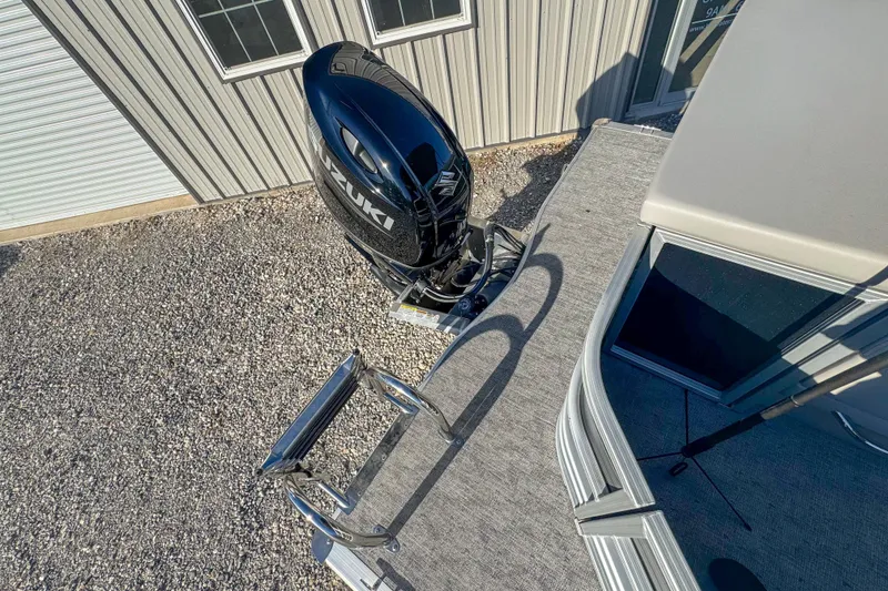 Slide: The Image of 2025 Berkshire 22CL LE pontoon boat with Suzuki outboard motor, docked near a building. - 11