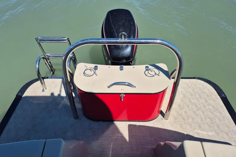 Slide: The Image of 2017 Avalon 2785 boat stern with motor, red storage, and swim ladder on calm water. - 12