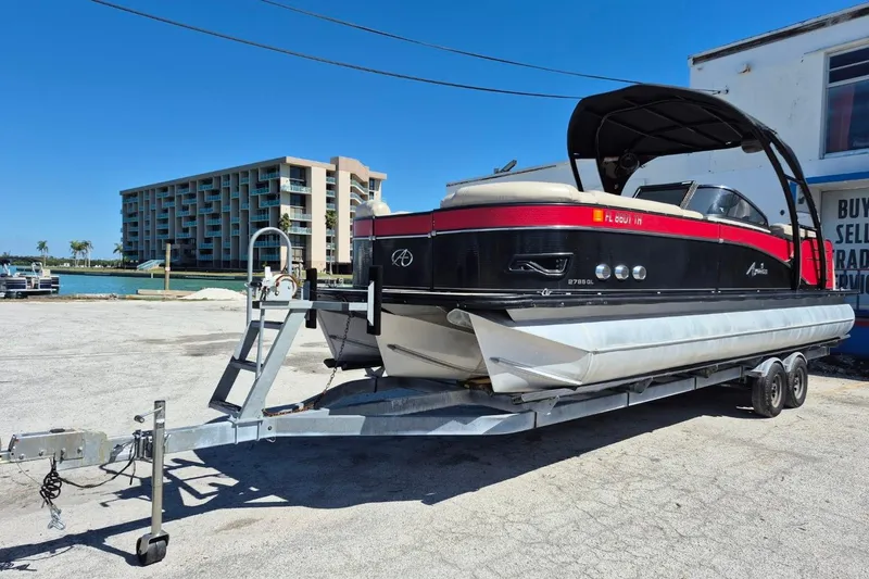 Slide: The Image of 2017 Avalon 2785 pontoon boat on trailer, parked near waterfront building. - 32