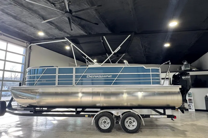 Slide: The Image of 2025 Berkshire 22RFC LE pontoon boat in showroom, featuring Suzuki outboard motor. - 1