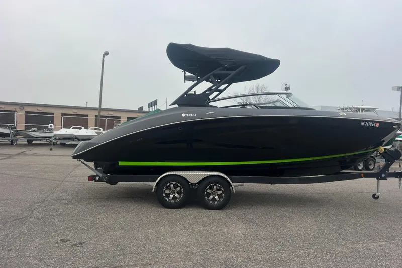 Slide: The Image of 2021 Yamaha Boats 255XD, black with green stripe, on trailer in parking lot. - 2